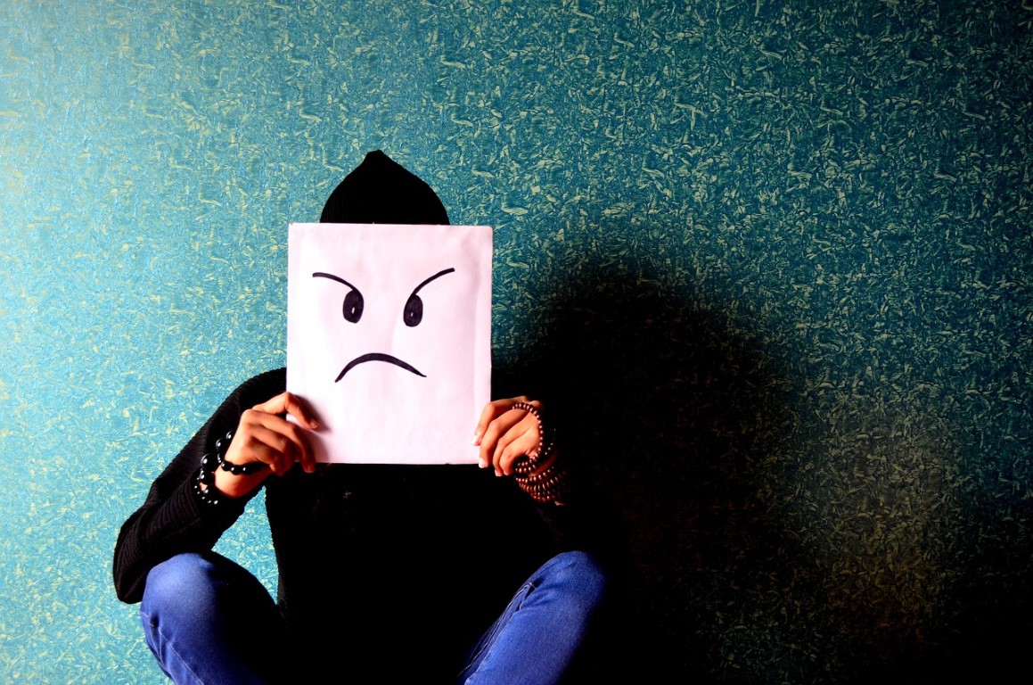 Billede af en person som sidder med et surt ansigt foran sit eget, sådan kan stress føles